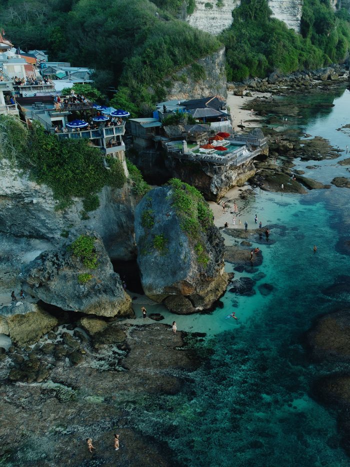 Aerial view of cliffside bars and pools above turquoise water at Suluban