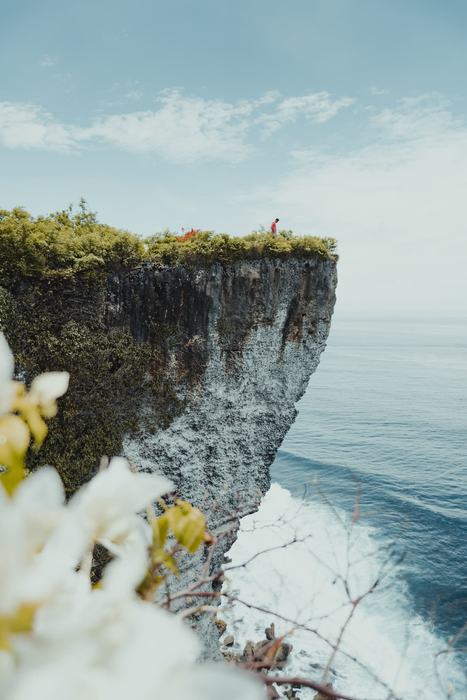 Person standing on the edge of the Uluwatu cliff above the ocean